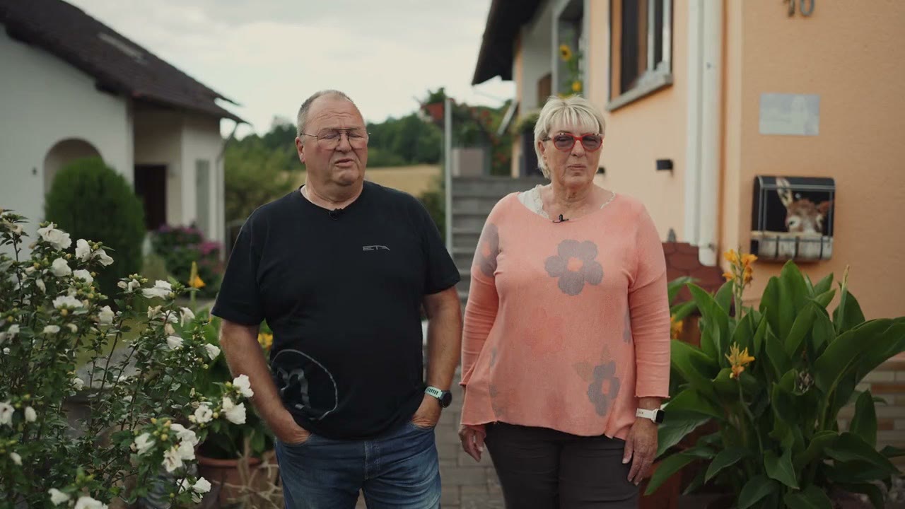 Zufriedenes Kundenpaar vor dem sanierten Eigenheim